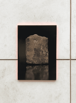 Artistic display of a rugged rock encased in a black frame with a subtle red backlight, showcased in the Virtual Vandalism AR exhibition. fabian-garna-cgi-art-direction